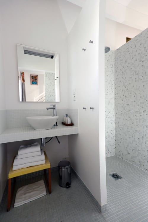 Salle de bains moderne de l'hôtel Côte et Dune avec lavabo blanc, miroir, douche en mosaïque et étagère de vanité en bois