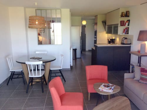 Séjour moderne avec salle à manger, fauteuils rouges, cuisine et balcon à Côte Et Dune, Biscarrosse Plage