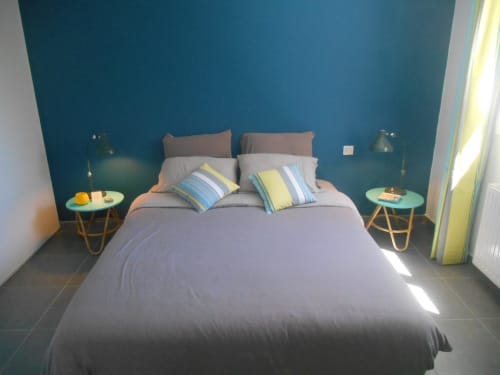 Chambre moderne à Côte Et Dune avec mur d'accent bleu-vert, literie grise, coussins rayés et tables de nuit turquoise à Biscarrosse