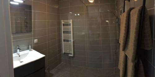 Salle de bain moderne à Cote Et Dune, Biscarrosse avec douche carrelée, lavabo blanc, porte-serviettes et sèche-serviettes.