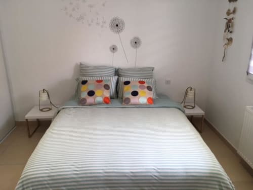 Chambre douillette de Côte Et Dune à Biscarrosse Plage, avec literie rayée, coussins colorés et décoration murale de pissenlits