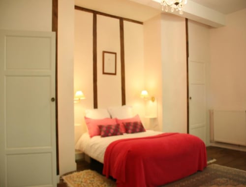 La chambre double Rose accueillante avec literie rouge, lit à baldaquin miroir, murs crème et éclairage chaleureux aux Cammazes