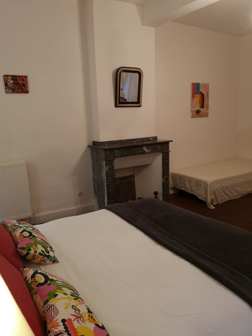 Chambre double à la L'affable B&B aux Cammazes avec coussins colorés, cheminée sombre et décoration murale