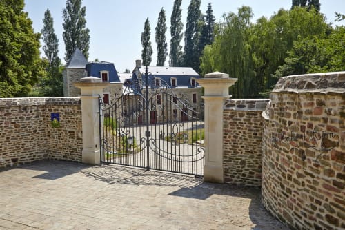 Portail en fer forgé orné de la maison d'hôtes Le Moulin d'Ajon à Maisoncelles sur Ajon, avec murs en pierre