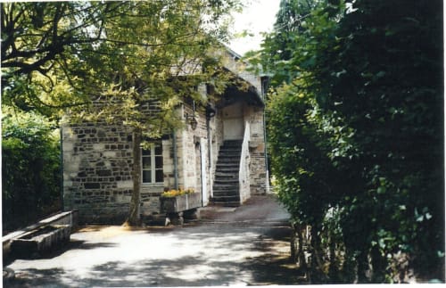 Entrée de la maison en pierre du gîte Le Moulin d'Ajon à Maisoncelles sur Ajon, entourée d'une verdure luxuriante