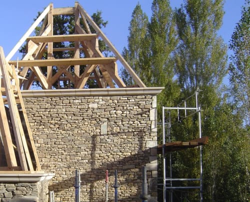 Bâtiment en pierre du moulin en restauration avec charpente en bois au Moulin d'Ajon, gîte en Maisoncelles sur