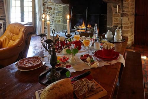 Table élégante au Moulin d'Ajon avec assiettes rouges, bougies, cheminée et pâtisseries frais à Maisoncelles sur Ajon