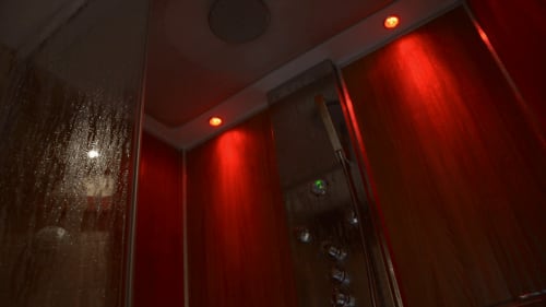 Salle de bain moderne avec douche et ambiance lumineuse rouge au Moulin d'Ajon, gîte français à Maisoncelles sur Ajon