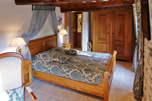 Lit rustique à quatre colonnes avec parure damassée bleue et baldaquin à la Chambre du Meunier du gîte Le Moulin d'Ajon,