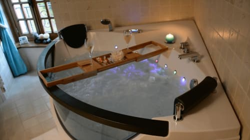 Spa luxueux avec éclairage d'ambiance et plateau en bois à la Chambre du Meunier du Moulin d'Ajon