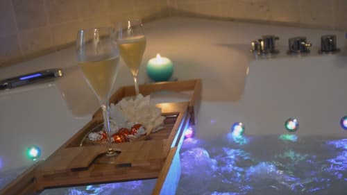 Salle de bain luxueuse avec champagne, bougies et éclairage ambiant à l'hôtel-boutique Le Moulin d'Ajon