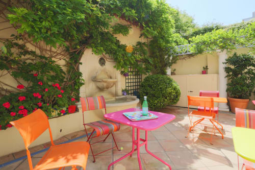 Terrazza-giardino al piano terra colorata dell'Hôtel De La Fontaine a Nizza con arredi vivaci e fiori in fiore
