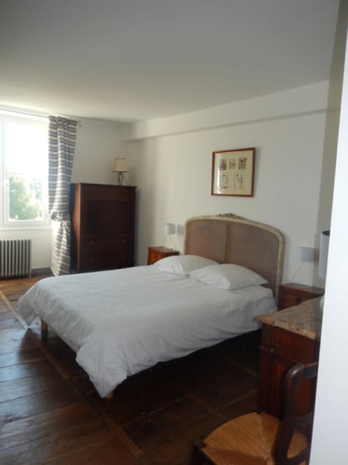 Chambre Charlotte du Domaine De Puyrousse à Villetoureix avec lit double, mobilier en bois et vue sur le jardin