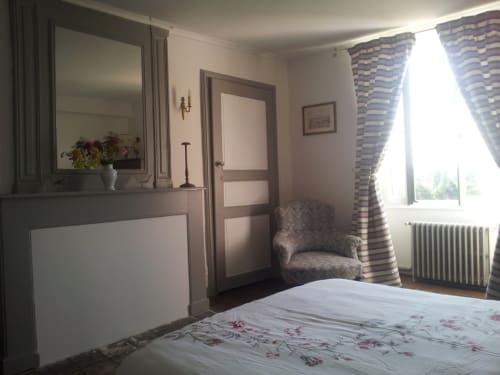 Chambre Charlotte au Domaine De Puyrousse, Villetoureix avec vue sur jardin, literie florale, miroir, fauteuil et décor rayé