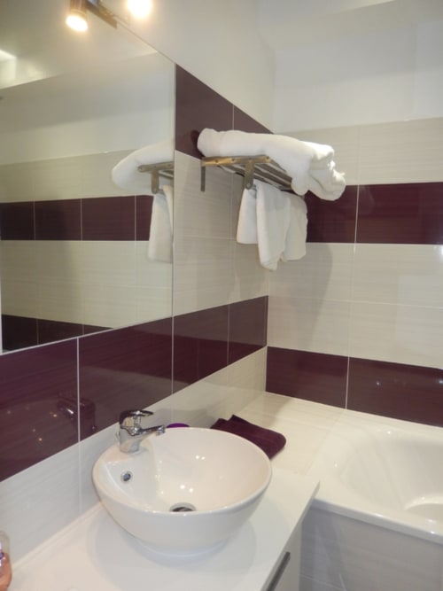 Salle de bain moderne de la Chambre Charlotte au Domaine De Puyrousse avec vasque ronde blanche, carrelage bourgogne et crème, et serviette