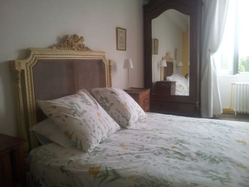 Chambre élégante au Domaine De Puyrousse avec tête de lit ornée, literie florale et miroir à Villetoureix