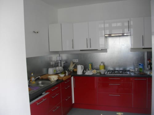 Cuisine moderne aux placards rouges et blancs, plan de travail noir et cuisinière à gaz au Domaine De Puyrousse, Villetoureix