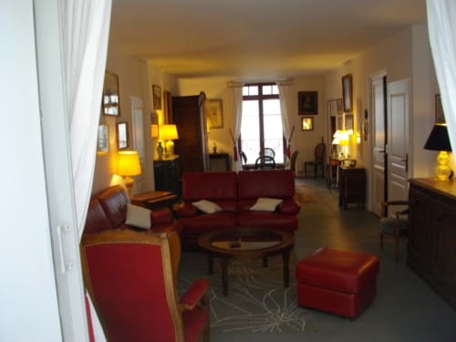 Élégant salon du Domaine De Puyrousse avec mobilier rouge, éclairage chaleureux et décoration classique à Villetoureix