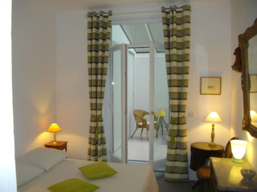 Chambre élégante du Domaine De Puyrousse avec rideaux verts rayés, éclairage doux et décoration moderne à Villetoureix