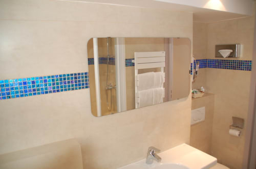 Bagno moderno all'Hôtel De La Fontaine a Nizza con accenti di piastrelle a mosaico blu, grande specchio e accessori doccia
