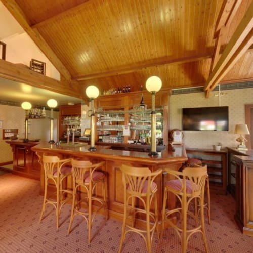 Bar et salon élégant à La Ferme Du Grand Air BnB à Fiennes, France avec luminaires suspendus et tabourets de bar
