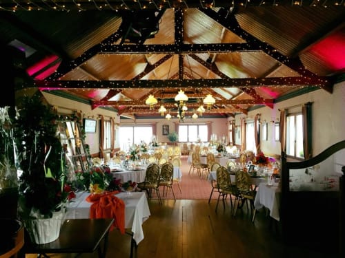 Salle de banquet élégante à La Ferme Du Grand Air à Fiennes avec plafond décorés, tables de restaurant et fleurs festives