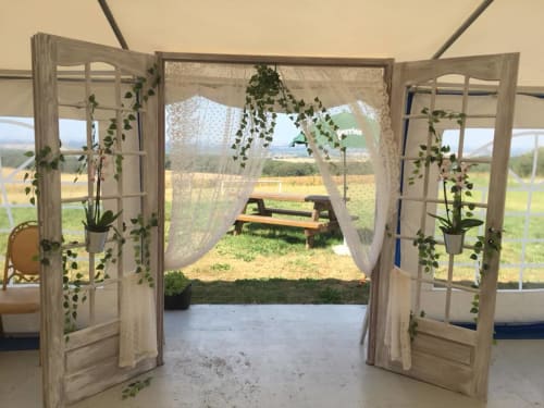 Portes rustiques en bois ouvrant sur la campagne à La Ferme Du Grand Air, Fiennes, avec plantes suspendues et mobilier extérieur.