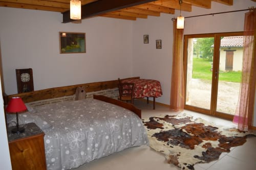 Spacieuse chambre Bugey à la Ferme Passion avec poutres apparentes, vue sur le jardin et mobilier rustique