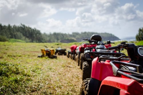 Des ATVs rouges alignés dans un champ vert à La Ferme Du Grand Air, un gîte d'aventure à Fiennes, France