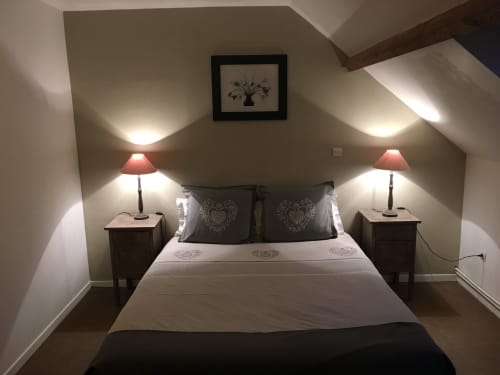 Chambre cosy sous les toits à La Ferme Du Grand Air avec lit double, deux lampes de chevet et vue sur le jardin