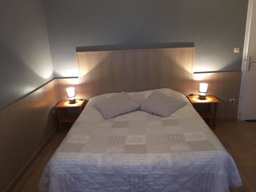 Chambre moderne à La Ferme Du Grand Air B&B à Fiennes avec literie blanche, tête de lit en bois et éclairage ambiant