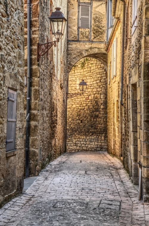 Narrow cobblestone alley at Domaine De Campagnac, Carsac-Aillac, with stone walls and vintage lanterns