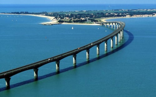 Long pont enjambant la baie turquoise près de La Rochelle, France avec ville côtière et plages de sable fin
