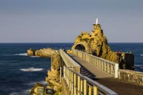 Dramatic coastal rock formation with white railings and arched tunnel overlooking Atlantic Ocean in Biarritz, France