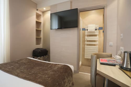 Camera d'hotel moderna all'Hôtel De La Fontaine a Nizza con letto, TV a parete, scrivania e bagno privato con doccia