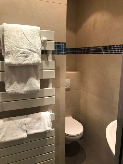 Bagno moderno presso l'Hôtel De La Fontaine Nice con portasciugamani, toilette e piastrelle con fascia azzurra