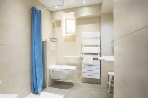 Bagno moderno della Suite Superior dell'Hotel De La Fontaine con toilette, doccia, scaldarancia riscaldato e piastrelle beige a Nizza