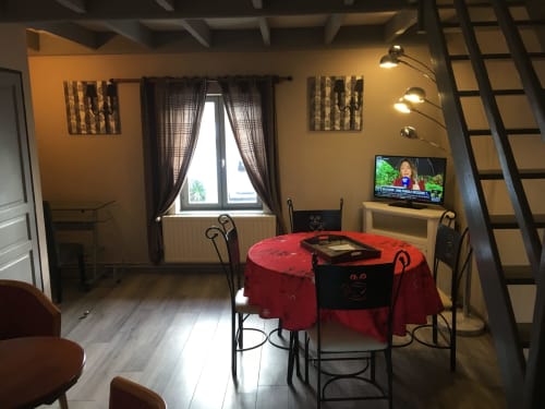 Salle à manger du Gîte avec table rouge, chaises noires, TV et ambiance chaleureuse à La Ferme Du Grand Air, Fiennes
