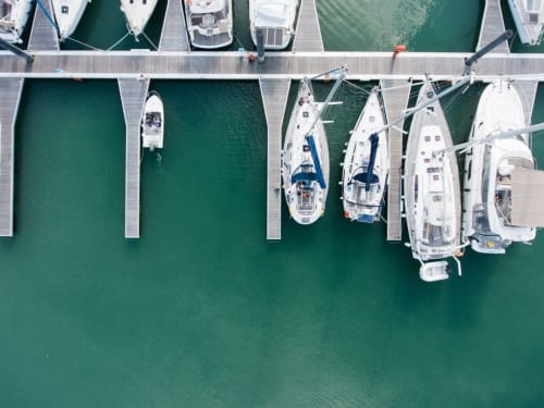 Vue aérienne de la marina L'escale Marine à La Rochelle avec voiliers blancs amarrés aux pontons en bois dans une eau turquoise