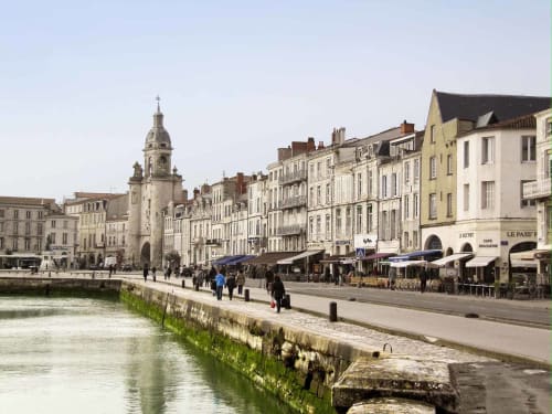Promenade en bord de mer à La Rochelle avec tour historique, bâtiments colorés, cafés et bateaux amarrés au port