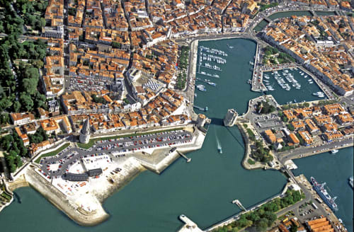 Vue aérienne de L'escale Marine B&B à La Rochelle avec bâtiments en terre cuite et marina côtière