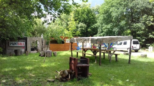 Zone de paintball au Domaine De Puyrousse avec tables de pique-nique, foyer et ambiance rustique à Villetoureix