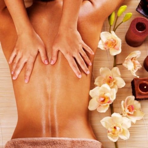 Relaxing back massage at Domaine De Campagnac spa in Carsac-Aillac, France with orchids and wellness decor
