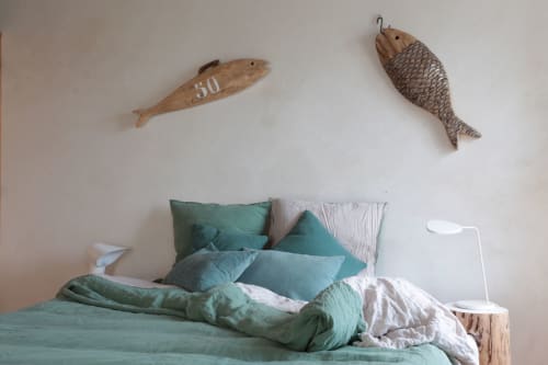 Chambre côtière avec literie bleu-vert, décoration murale poissons en bois et lampe blanche aux Filles du Bord de Mer