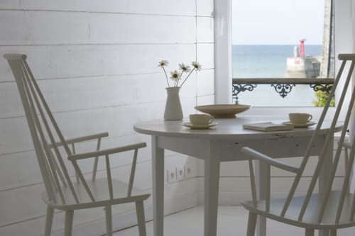 Coastal dining room at Les Filles du Bord de Mer with white furniture, fresh flowers, and ocean view overlooking