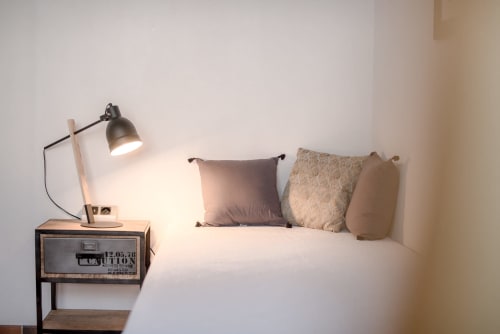 Chambre épurée au gîte Le Pignié avec lit, oreillers décoratifs, table de nuit en bois et lampe de bureau à Lescure-d'Albigeois