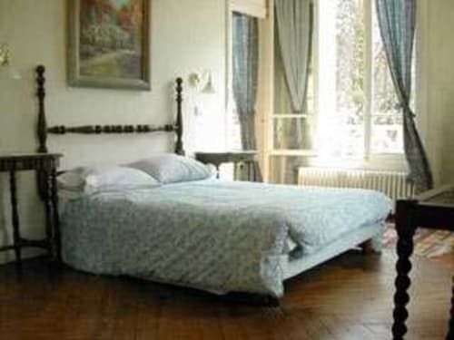 Chambre élégante avec lit à baldaquin noir, literie bleu clair et vue sur le jardin au Chalet Du Bel Event