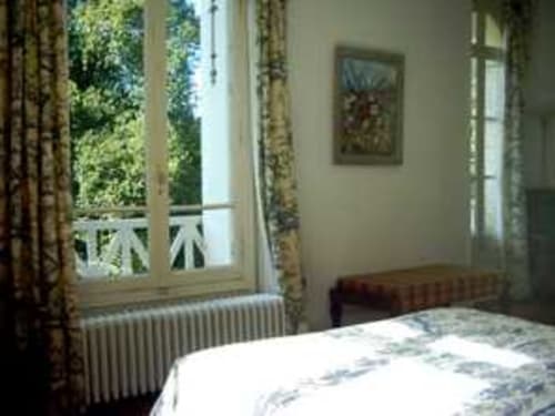Chambre lumineuse avec vue sur le jardin au Chalet Du Bel Event à La Chapelle-sur-Dun, avec lit blanc, bureau et portes-fenêtres
