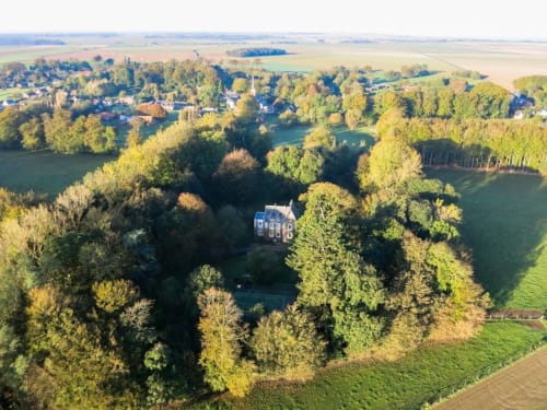 Aerial view of Chalet Du Bel Event, a brick mansion nestled in woodlands near La Chapelle-sur-Dun, France