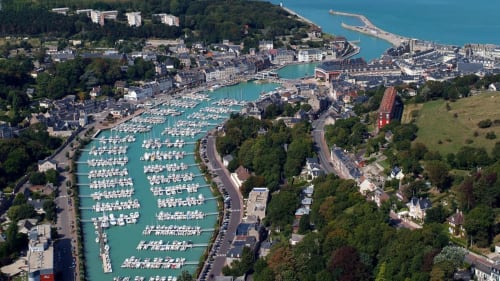 Aerial view of Honfleur harbor with turquoise water, moored boats, and coastal town near Chalet Du Bel Event in La